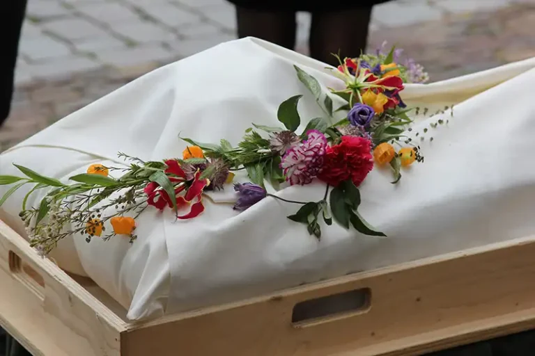 Opgebaarde kist met bloemen, Christine Veldhoen Uitvaartzorg